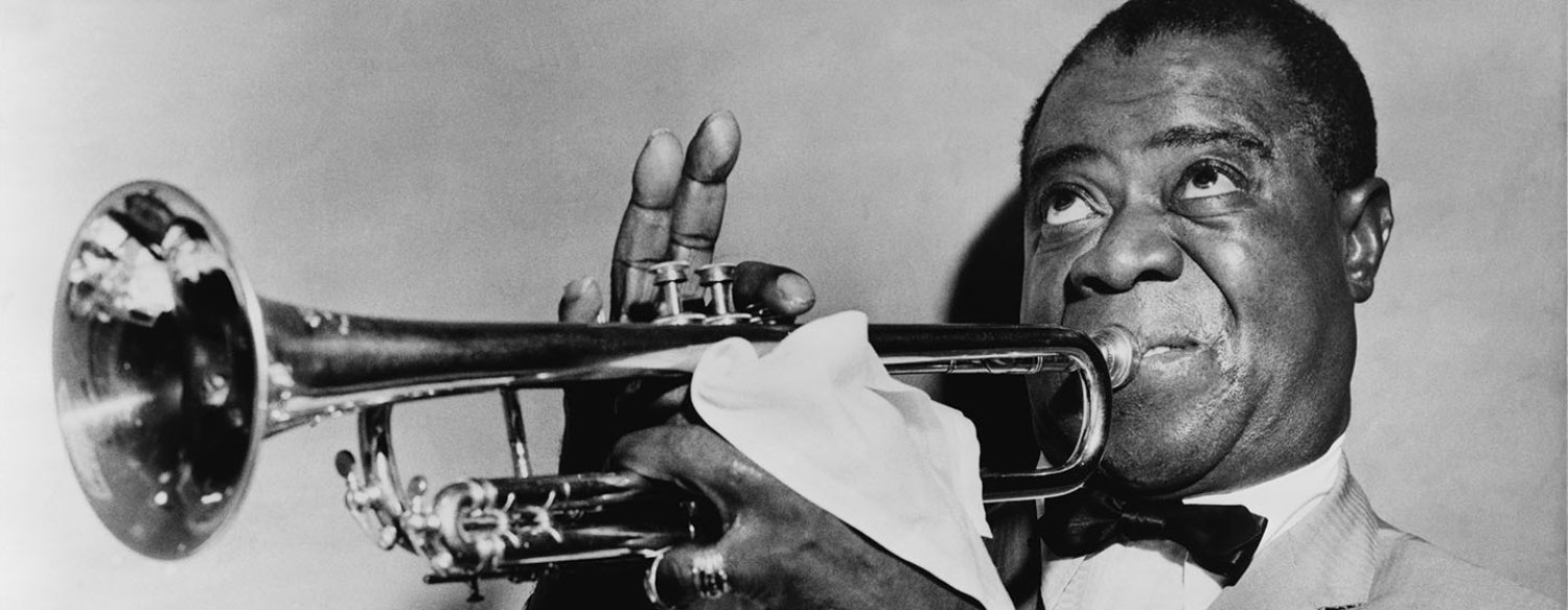 A black-and-white photo of Louis Armstrong playing the trumpet, taken in 1953.