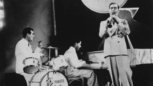 Black-and-white photos showing The Benny Goodman Trio performing, with Benny Goodman on the trumpet, Gene Krupa on the drums, and Teddy Wilson on the piano, in 1937. | Music 101