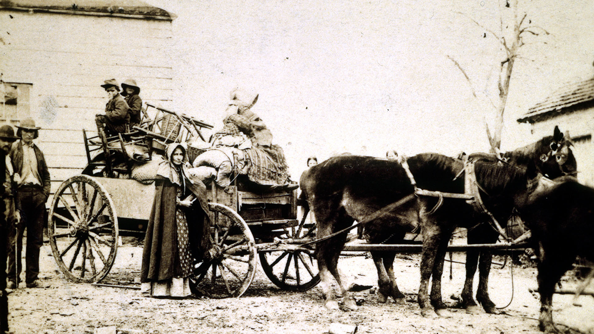 A sepia-toned photo showing a southern refugee family loading a horse-drawn wagon with their furniture and belongings.