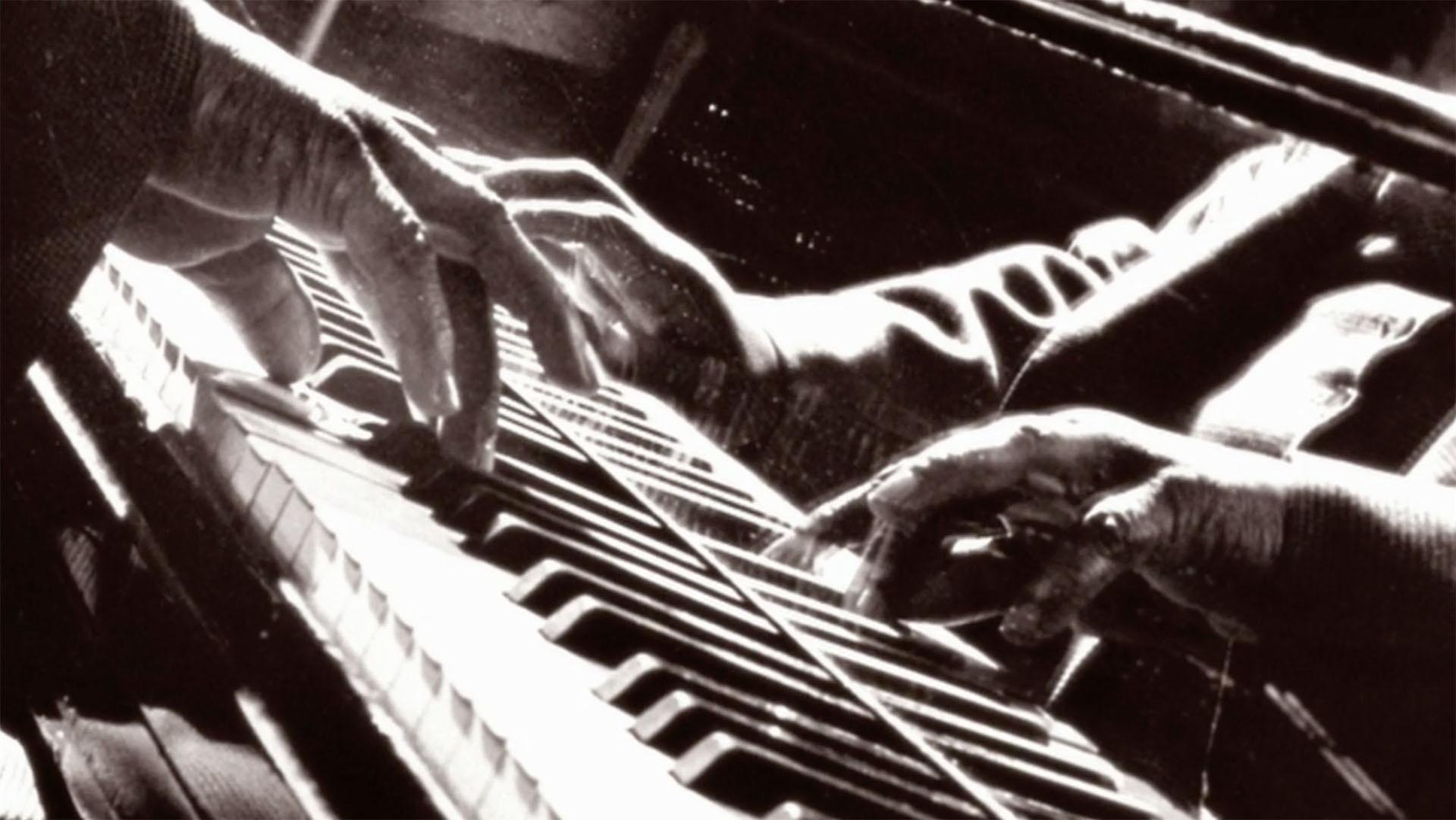 A black-and-white image of someone's fingers on piano keys.