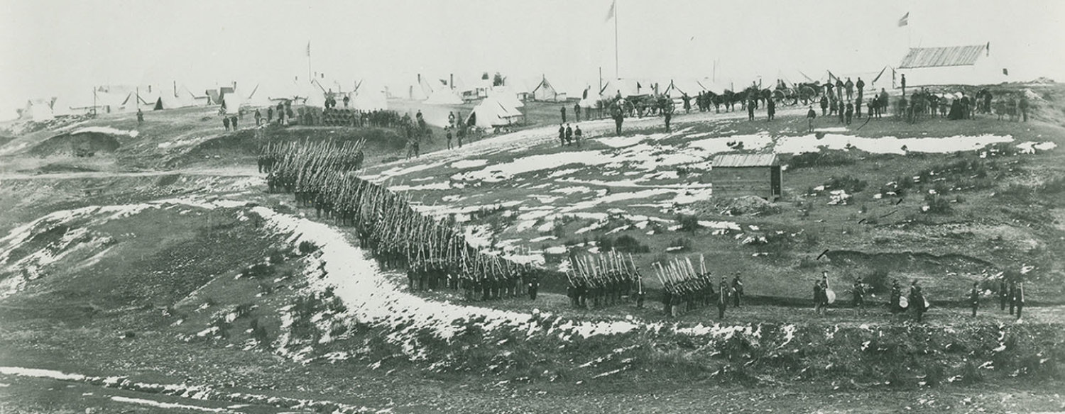 A black-and-white photo showing Union troops conducting drills on snow-blanketed hills near Washington, D.C., circa 1861–65.