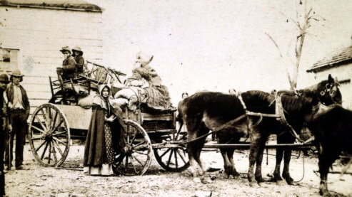 A sepia-toned photo showing a southern refugee family loading a horse-drawn wagon with their furniture and belongings. | Photo Gallery