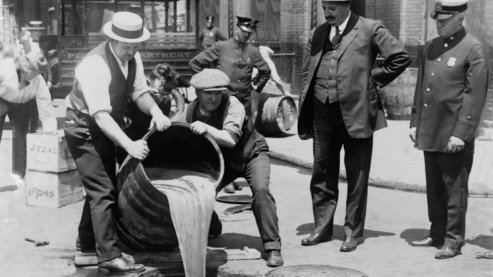 New York City Deputy Police Commissioner John A. Leach, right, watching agents pour liquor into sewer following a raid, ca. 1921. After the Mullan-Gage Act was repealed in 1923, New York police were no longer bound to enforce Prohibition. | Video