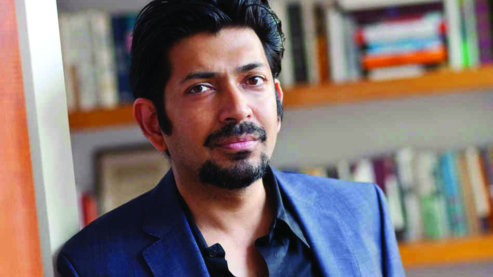 Photograph of Dr. Siddhartha Mukherjee with a bookshelf in the background. | About the Film